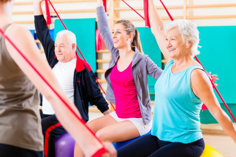 Ältere Menschen beim Fitnesstraining im Fitnessstudio mit einem Stretchband.